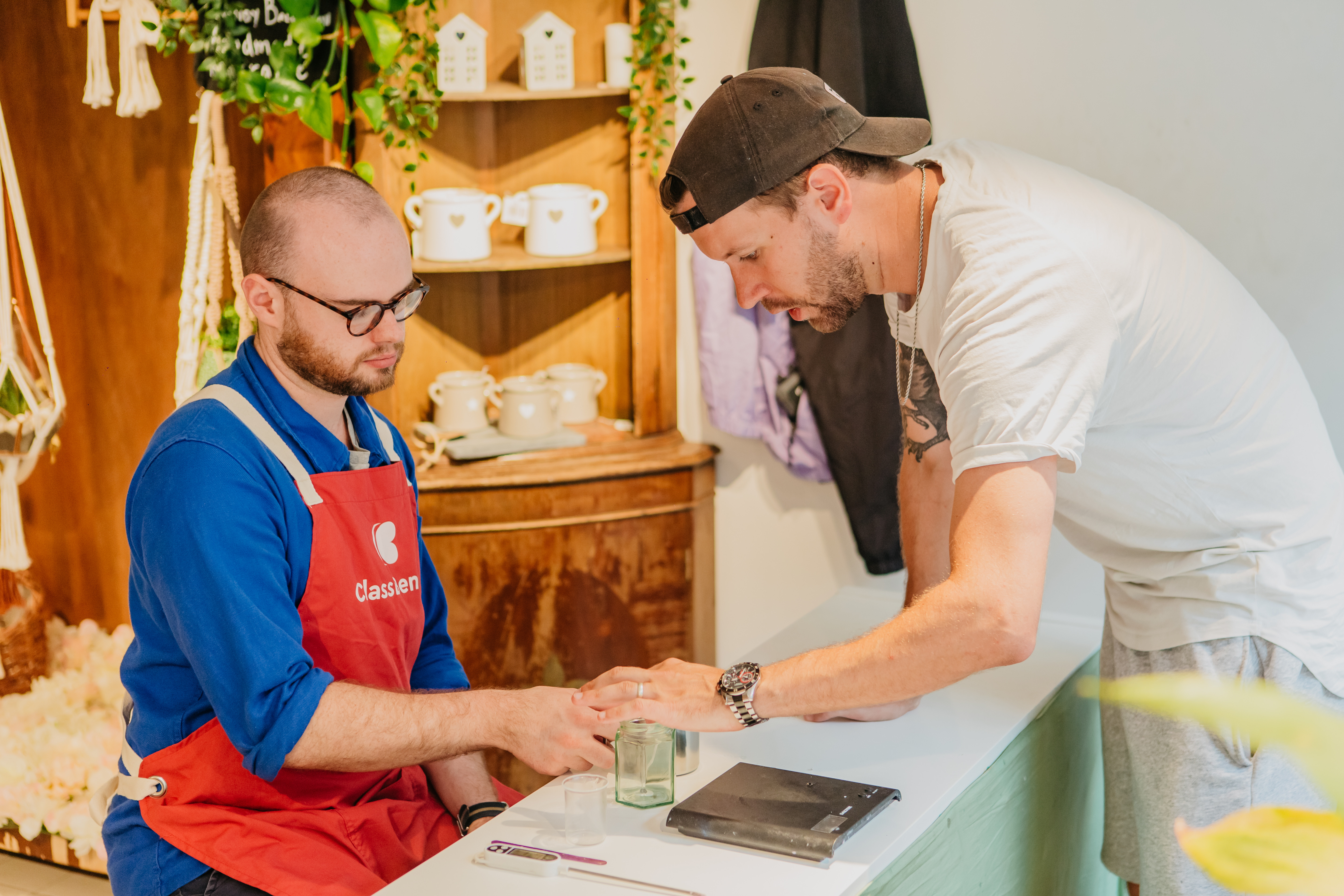 A teacher showing a student how to pour a candle